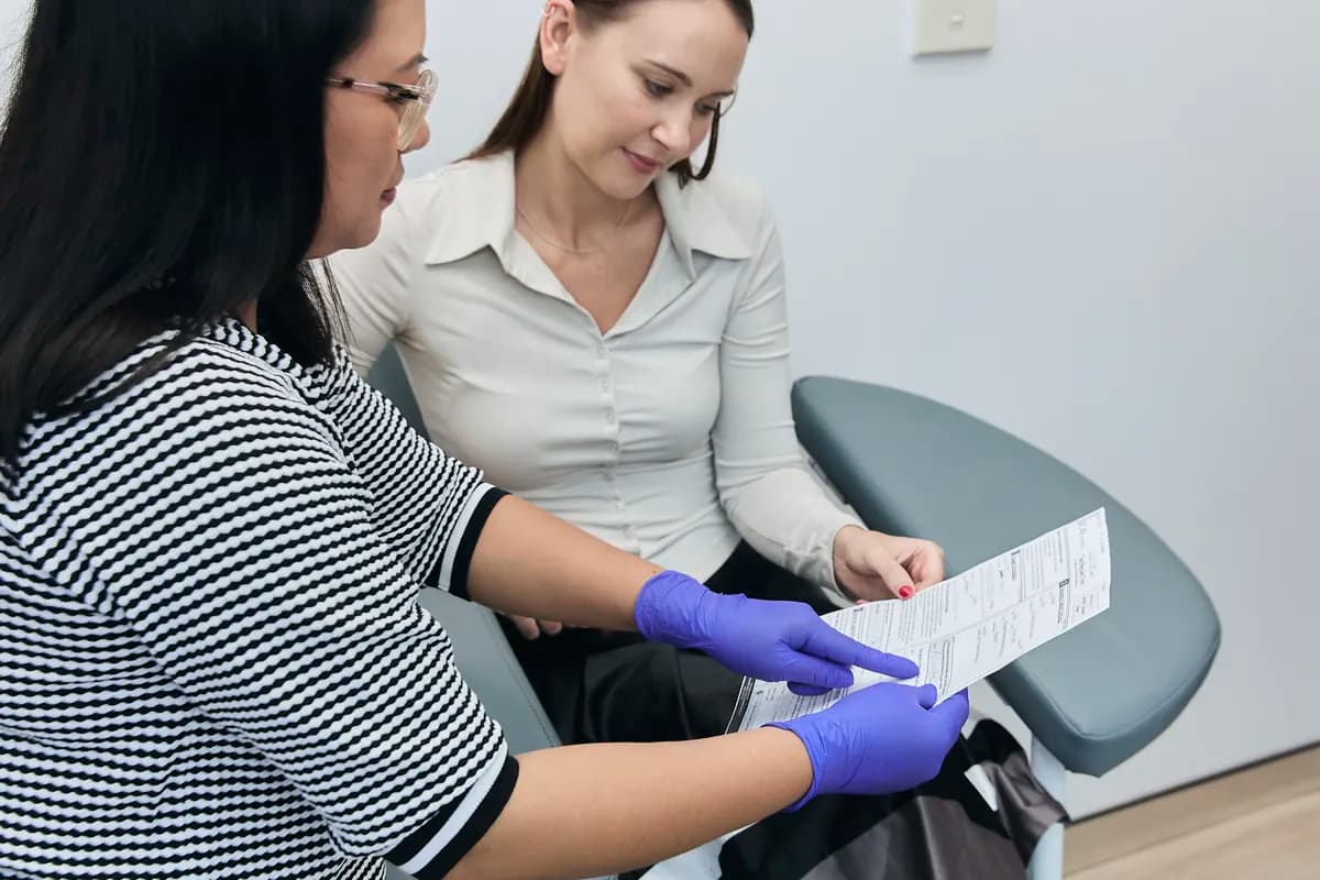A clinician in gloves reviewing a document with a patient